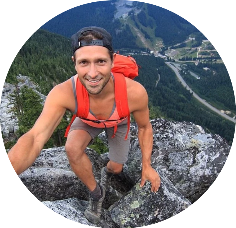 caucasion man in a tank top smiling at the camera form above while climbing 